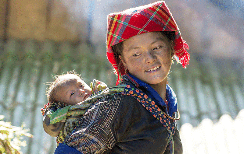 Une femme Hmong de Mu Cang Chai porte son enfant sur son dos pendant qu'elle travaille dans les champs.